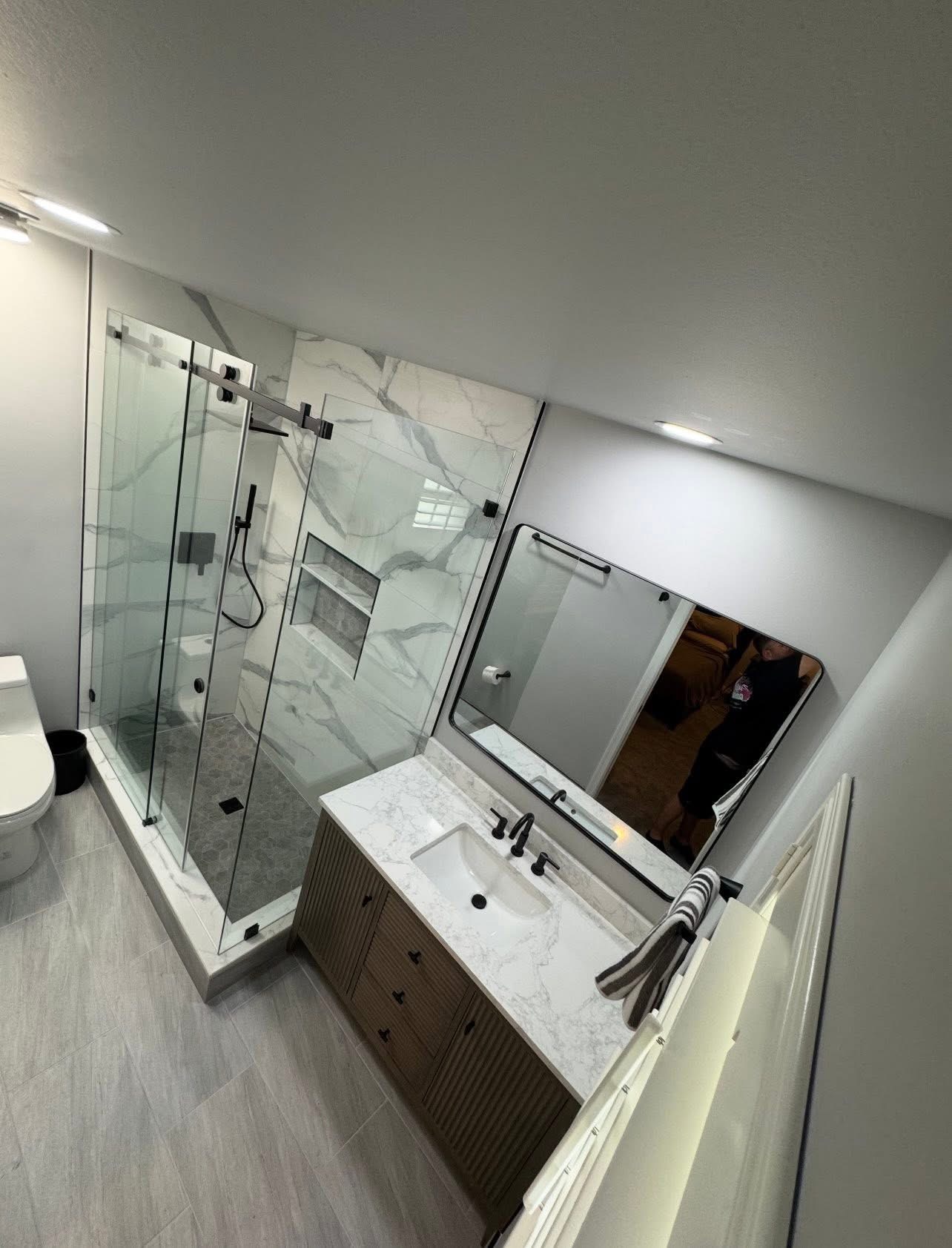Marble shower with matte black fixtures and fluted vanity