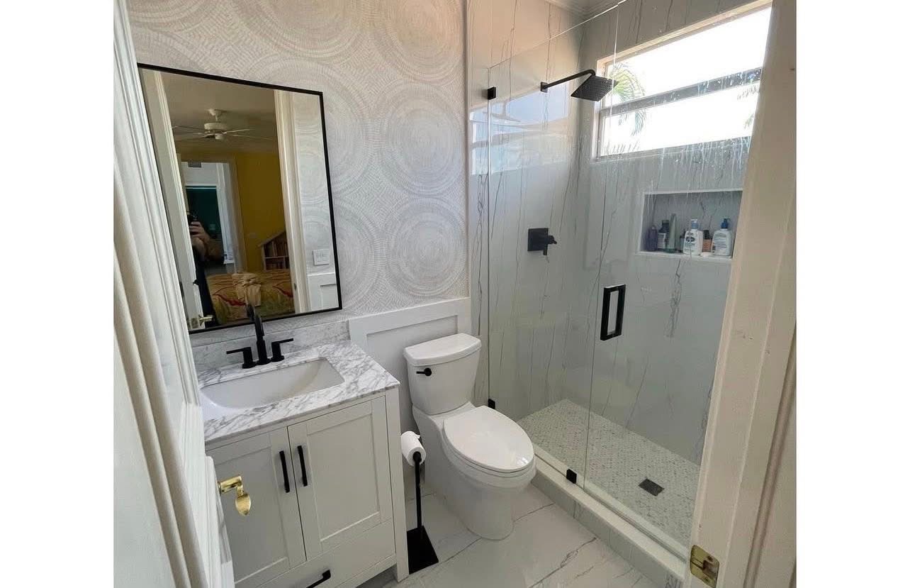 Guest bath with frameless glass shower and patterned wallpaper