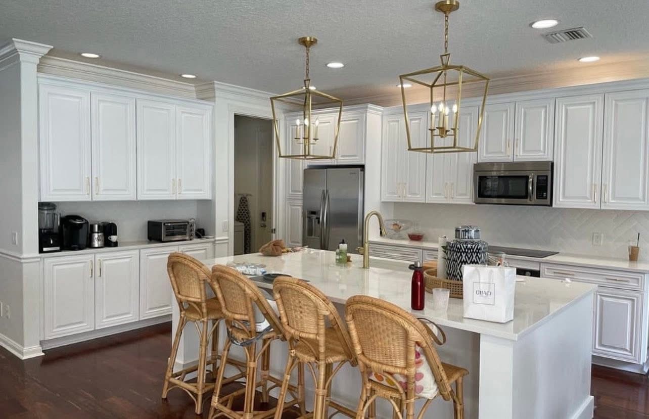 White kitchen with brass lantern pendants and quartz island