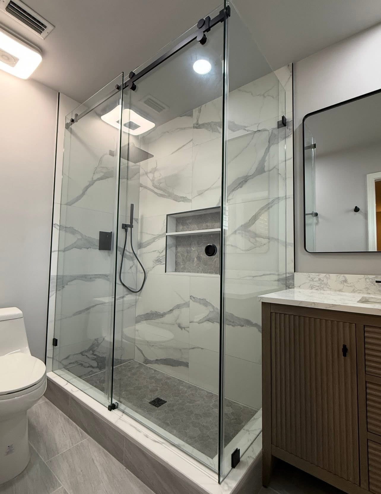 Frameless glass shower with book-matched marble slabs