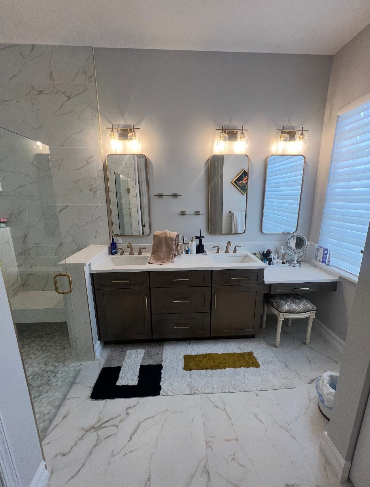 Double vanity with arched mirrors and marble shower