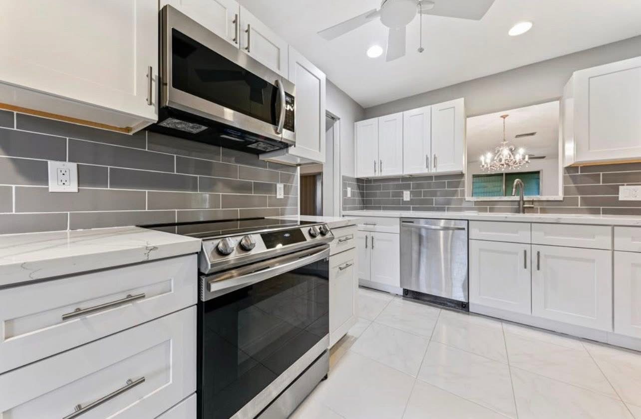 Galley kitchen with grey subway tile and quartz counters