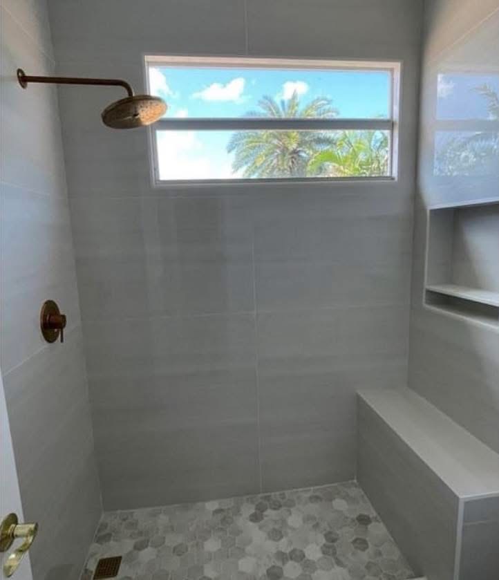 Walk-in shower with built-in bench and tropical view